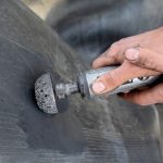 Worker using tire grinder machine for tire repairing